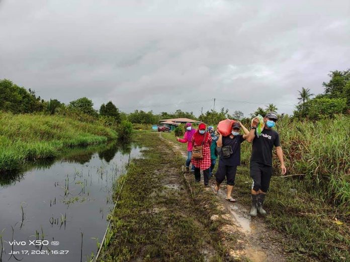 TIDAK MENGENAL CABARAN…Siti Aminah (Tiga di belakang) bersama rombongan terpaksa meredah lumpur untuk menhantar sumbangan di salah sebuah kampung di DUN Klias baru-baru ini.