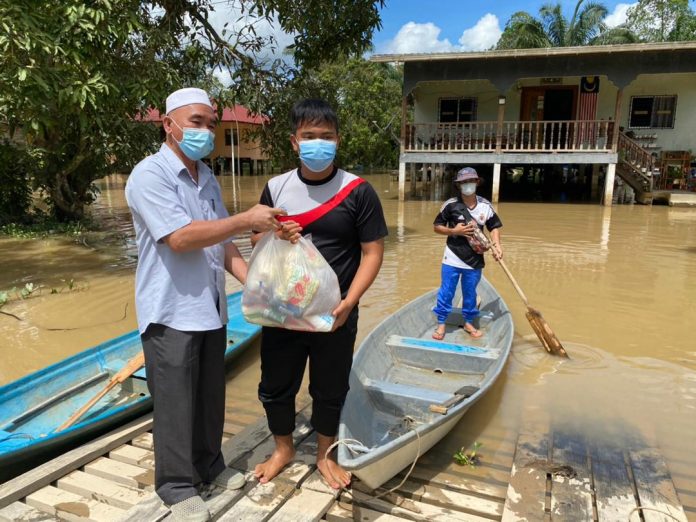 Ruslan presenting food contribution to a flood victim at Kampung Suasa, Beaufort