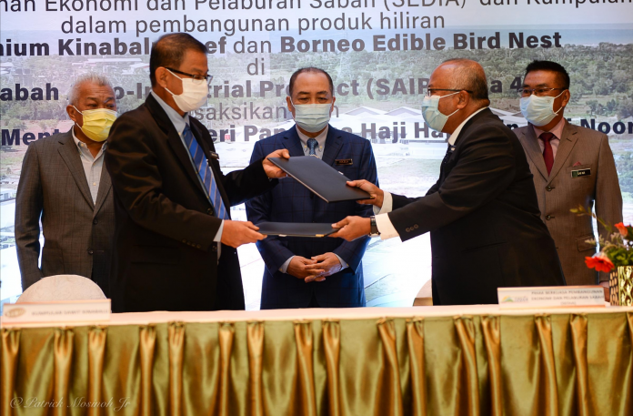 Sawit Kinabalu Group Managing Director Bacho Jansie (Left) exchanging documents with Sedia CEO Datuk Hashim Paijan (right) that was witnessed by Chief Minister, Datuk Seri Hajiji Haji Noor (Centre).