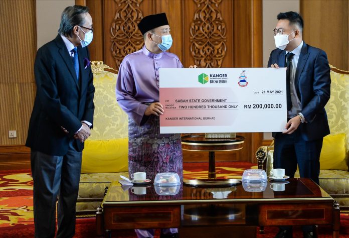 Hajiji receiving the replica cheque for RM200,000 from Kanger International Bhd Executive Director Steven Kuah (right) while Local Governmetn and Housing Minister Datuk Seri Masidin Manjun (left) looks on at PPNS yesterday.
