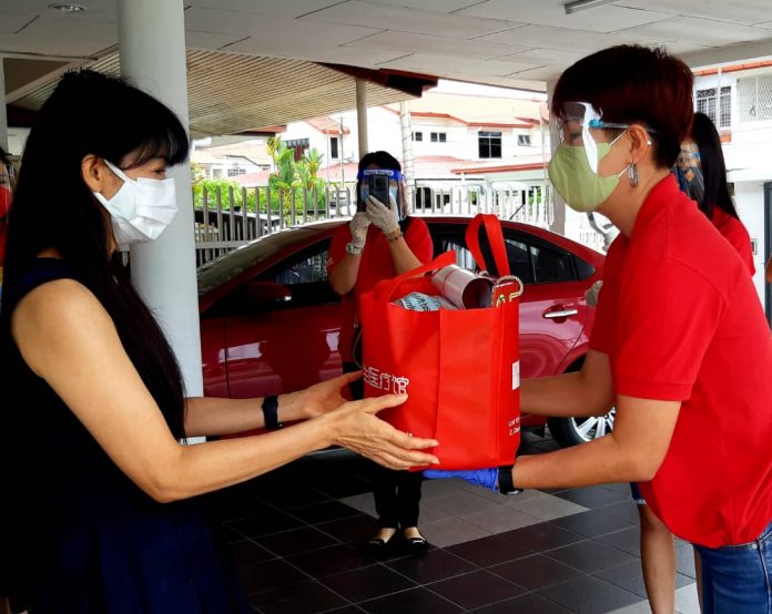 The Borneo Go delivery team (in red) presents a festive gift to a woman.
