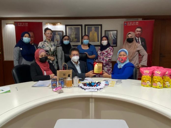 Dr Joachim (duduk, tengah) menerima cendera kenangan daripada Dr Tarsiah TZ (duduk, kanan) di Wisma Kewangan, Kota Kinabalu.