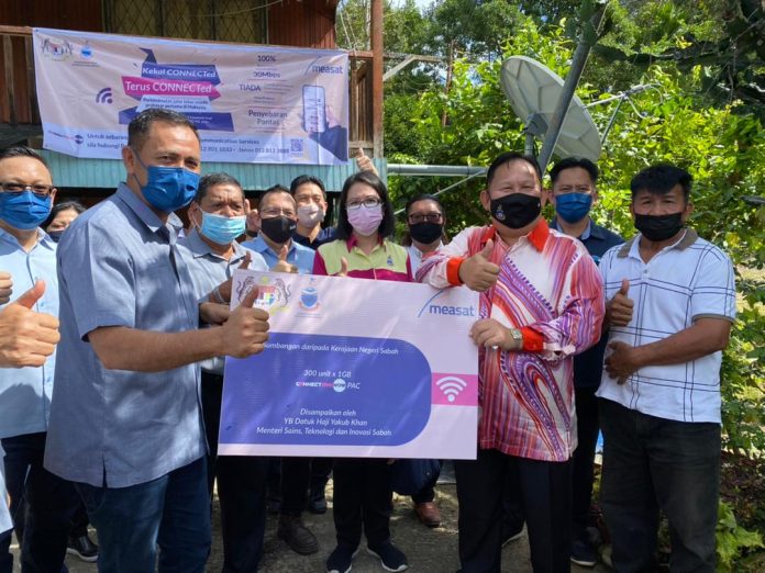 Datuk Yakub Khan menyerahkan kemudahan wifi kepada Juil Nuatim sebagai simbolik pelancaran pemasangan Connectme Now di Kampung Gana, Papar.