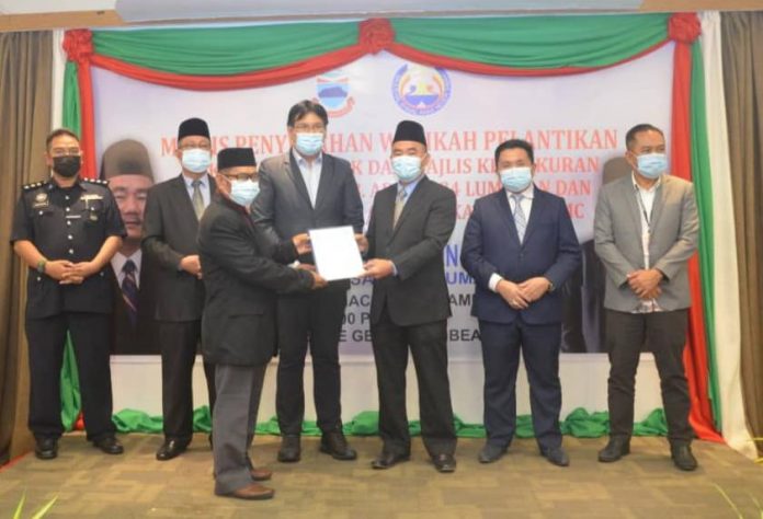 Hj Ruslan (tiga, kanan) menyampaikan watikah pelantikan kepada ketua adat bagi kawasan DUN Lumadan, yang diperhatikan oleh Hj. Yamani Hafez Tan Sri Musa dan Matbali Musah.