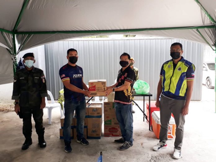Mositun (right) handing over the drinks to a representative at the roadblock in Kampung Mook