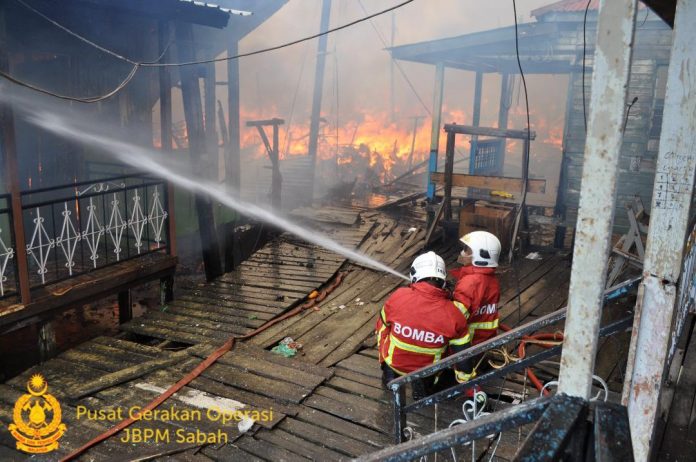 Firefighters fighting fire at Kg. Titingan in Tawau.