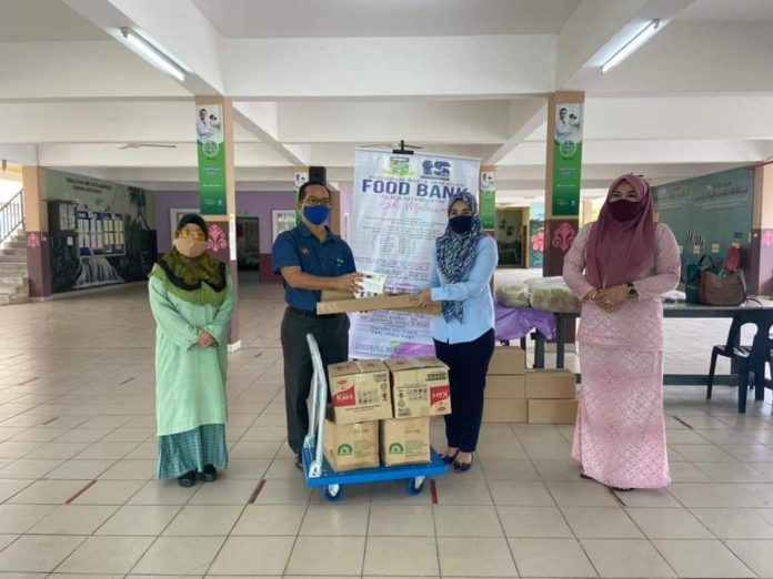 SERAH..Kelihatan Dr Fadilah menyerahkan alat penyukat suhu badan kepada Guru Besar Sk Malawa Jaimie Mosliem semasa program tersebut